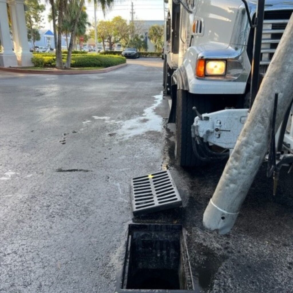 a truck with a tube down a sewer grate